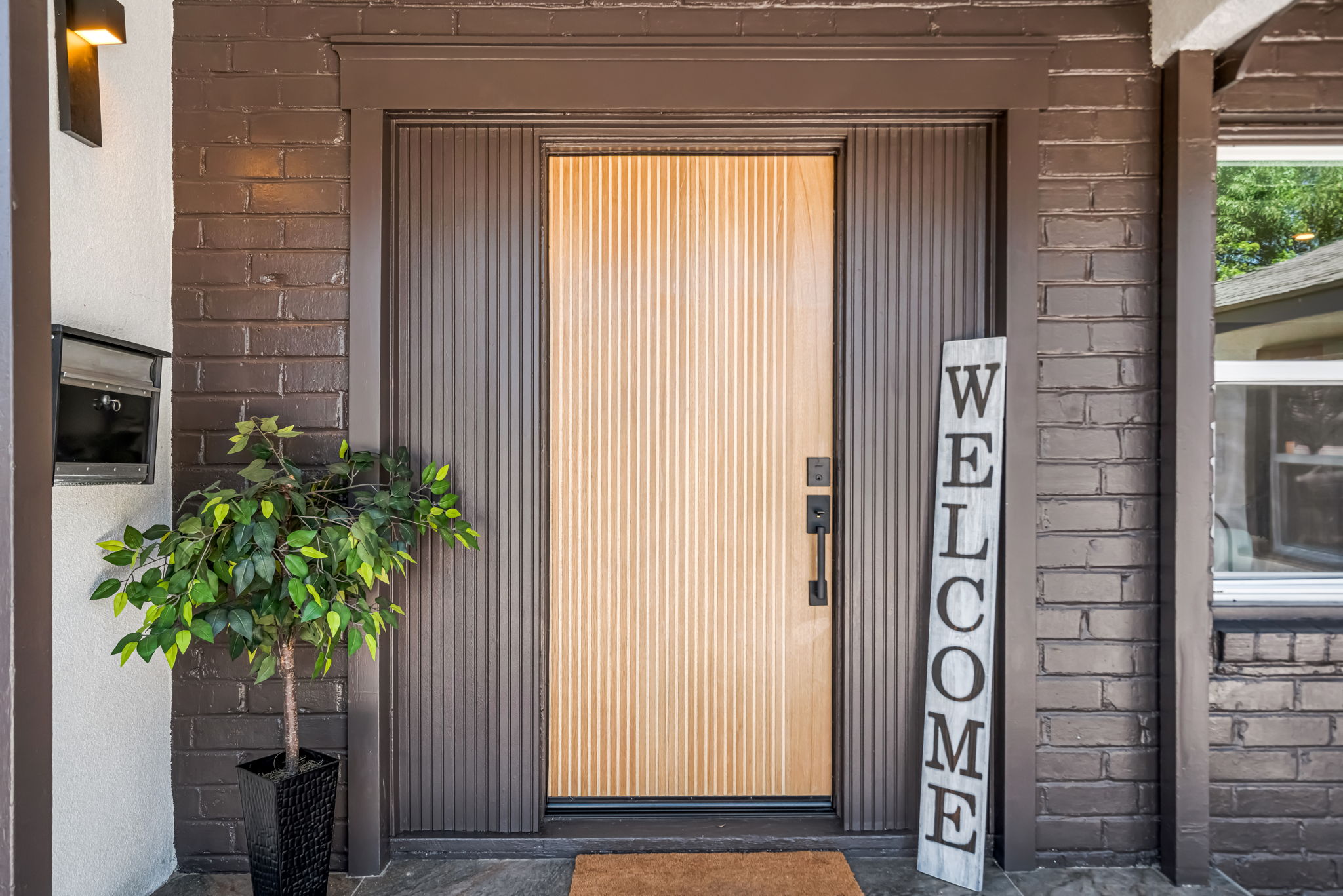 Modern slatted wood front door with Welcome sign
