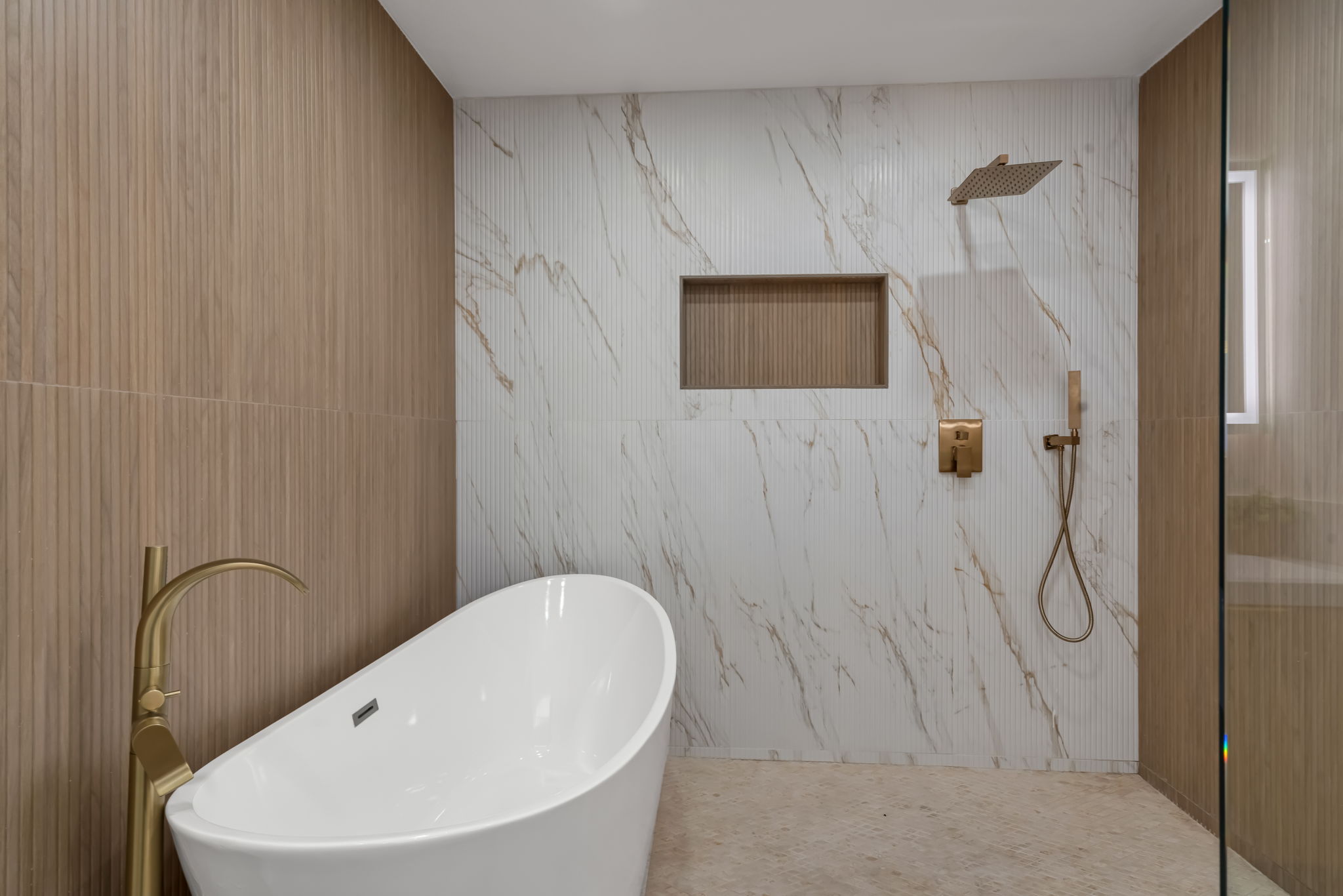 Spa bathroom — freestanding tub, marble tile, rain shower, gold fixtures